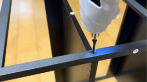 変形電動ドライバーでスチールラックのネジを締めている様子