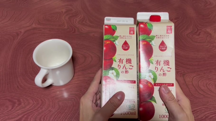 開封した内堀醸造の有機りんごの酢ストレートタイプ1Lを2本並べ、カップと一緒に手に持った様子