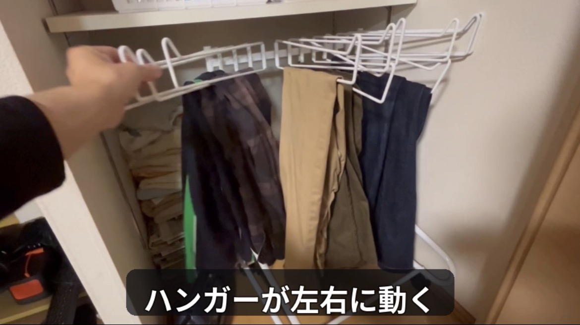 ズボンを掛けた金属製ハンガーを左右に動かして取り出す様子