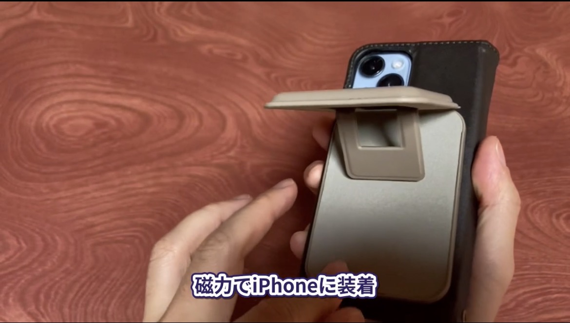 iPhone14の背面にカードケース型充電器を装着し、スタンドを開いた様子